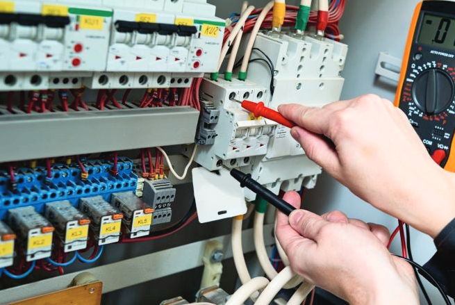 Engineer testing an electrical control panel with a digital multimeter